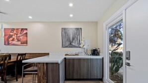Een moderne keuken met een centraal eiland, houten kasten en een eethoek met een houten tafel en stoelen.