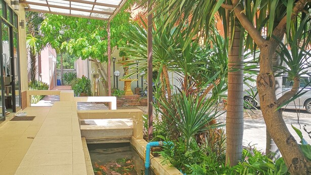 A covered walkway with a water feature and various plants. - The Wonders Hotel (Chaiyaphum)