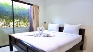 A hotel room with a large bed, white linens, and a heart-shaped towel arrangement on the bed. - The Wonders Hotel (Chaiyaphum)