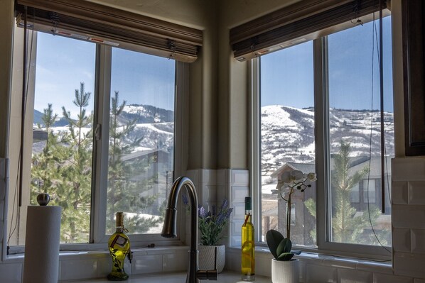 A kitchen with a large window overlooking a snowy landscape.