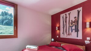 Un dormitorio con cama, ventana, una obra de arte en la pared y una mesita de noche.