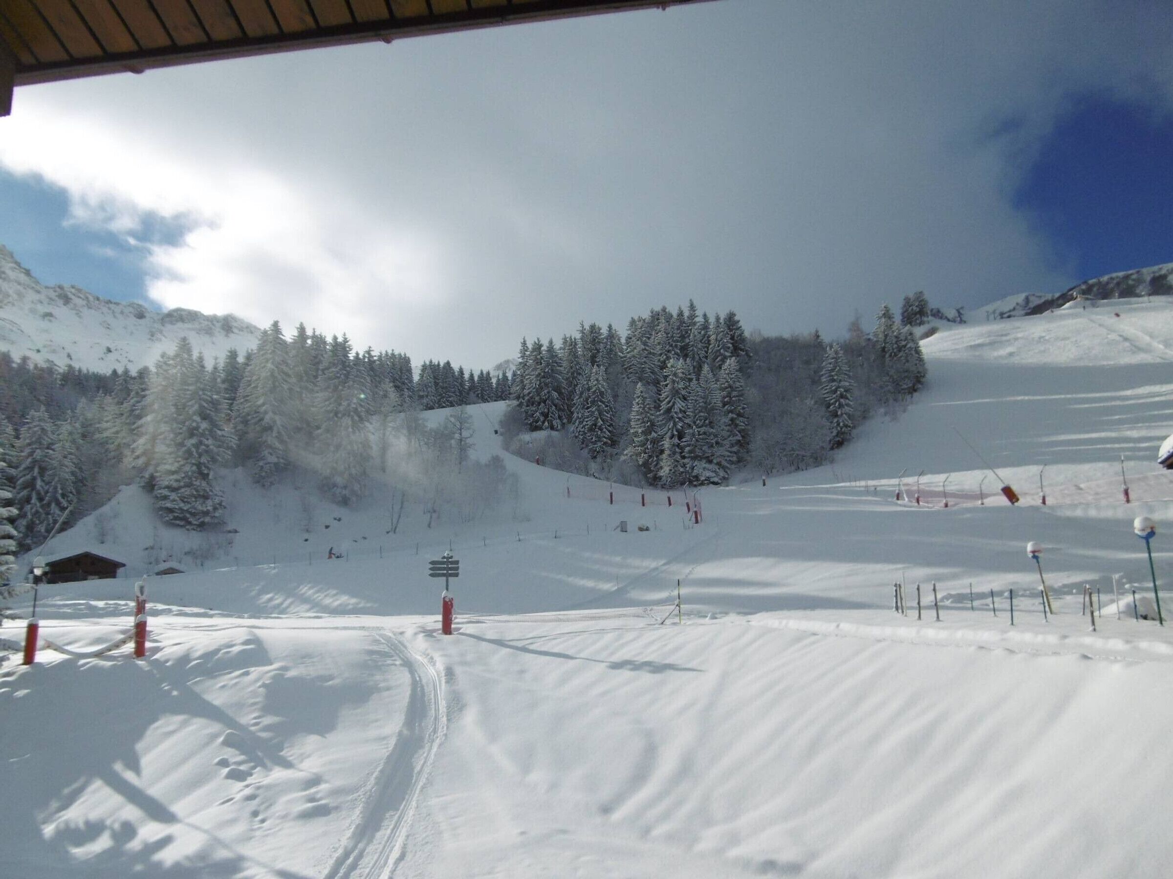 Une piste de ski enneigée, avec un télésiège et un chalet en bois en arrière-plan.