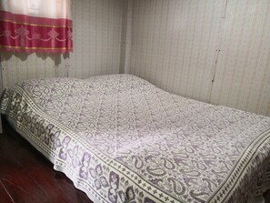 A single bed with a patterned bedspread in a room with striped wallpaper and a wooden floor. - Phaiwan Baansawn Resort (Chai Nat)