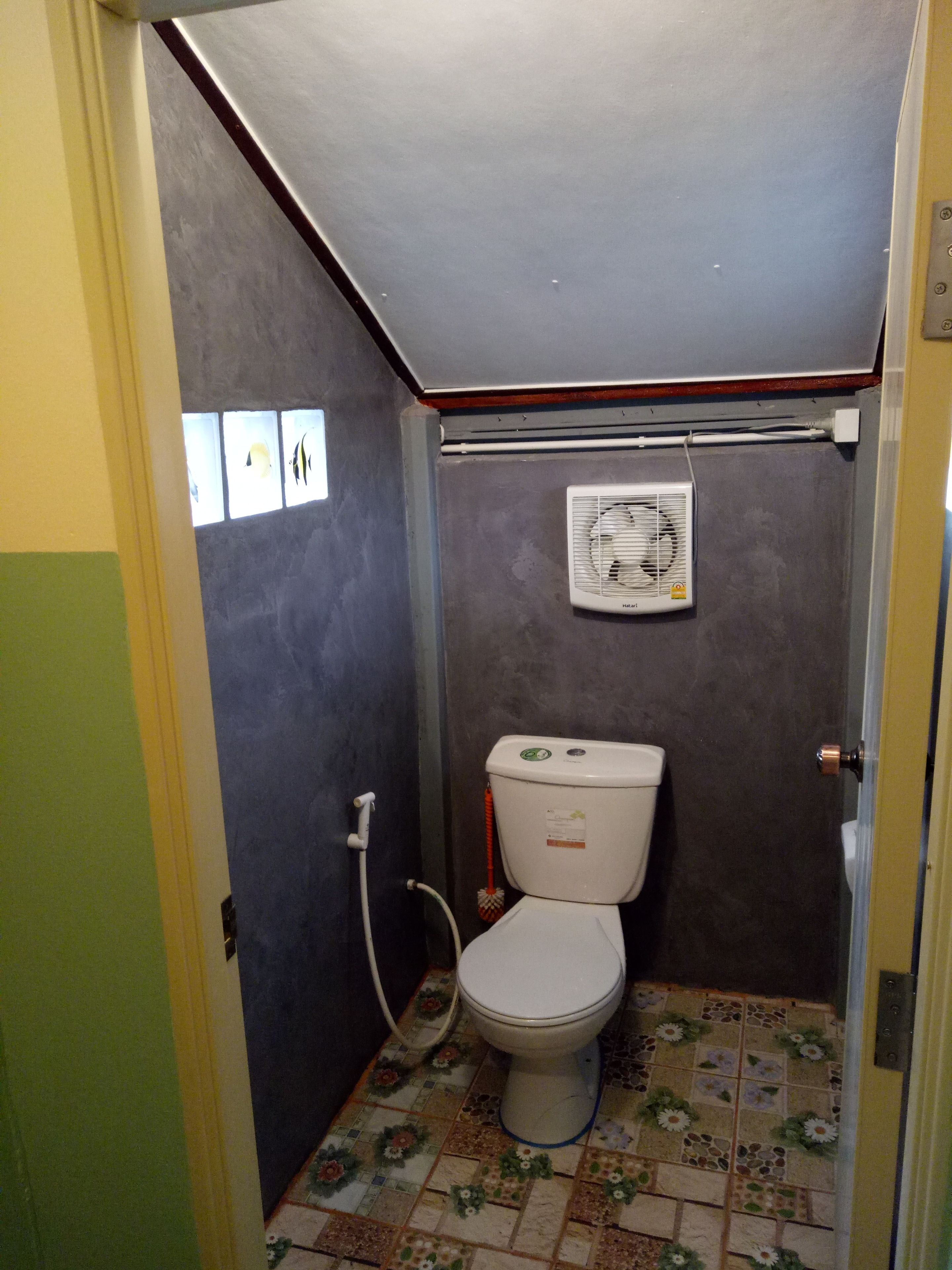 A small bathroom with a toilet, a shower, and a wall-mounted air conditioner.
