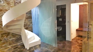 A spiral staircase with a glass door leading to a bathroom.