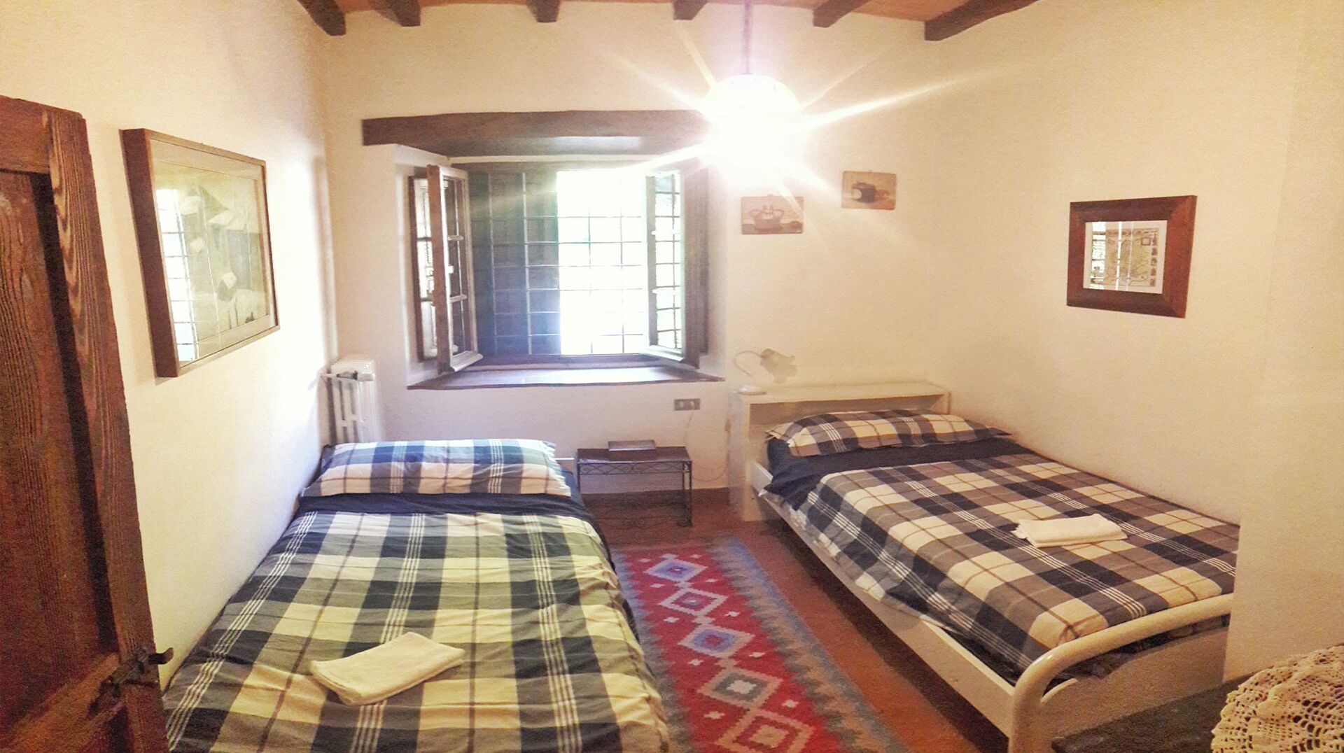 A small, cozy room with two beds, a window with a view, and a radiator.