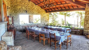 A rustic outdoor dining area with stone walls, wooden tables, and chairs.