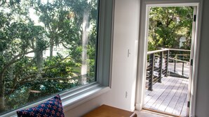A room with a large window, a wooden bench, and a view of a balcony with railings. - Stunning Stono River Guesthouse w/ Scenic Water Views &  Pool (Charleston)