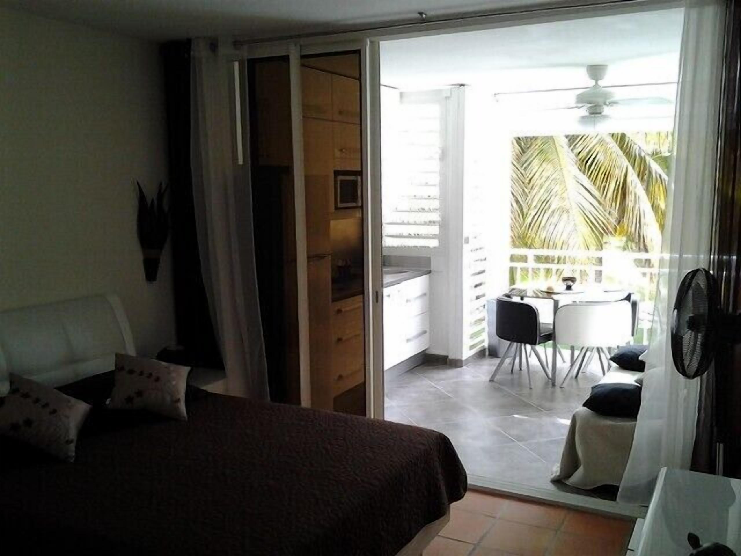 A bedroom with a bed, a sliding door to a balcony, a small table, and chairs.