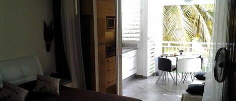 A bedroom with a bed, a sliding door to a balcony, a small table, and chairs.
