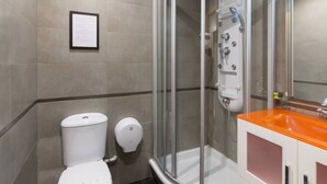 A modern bathroom with a glass-enclosed shower, a white toilet, and a sink with an orange countertop. - Bright apartment T3 (Tours)