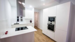 A modern kitchen with white cabinetry, a built-in oven, and a microwave. - Bright apartment T3 (Tours)