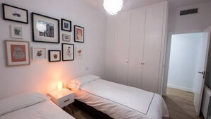 A bedroom with two single beds, a nightstand, a wall-mounted light, and a wardrobe. - Bright apartment T3 (Tours)