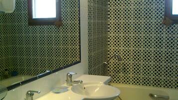 Een bad/douchecombinatie, een haardroger, handdoeken, toiletpapier