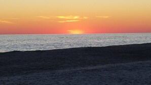 Una playa al atardecer con cielo despejado y mar tranquilo.