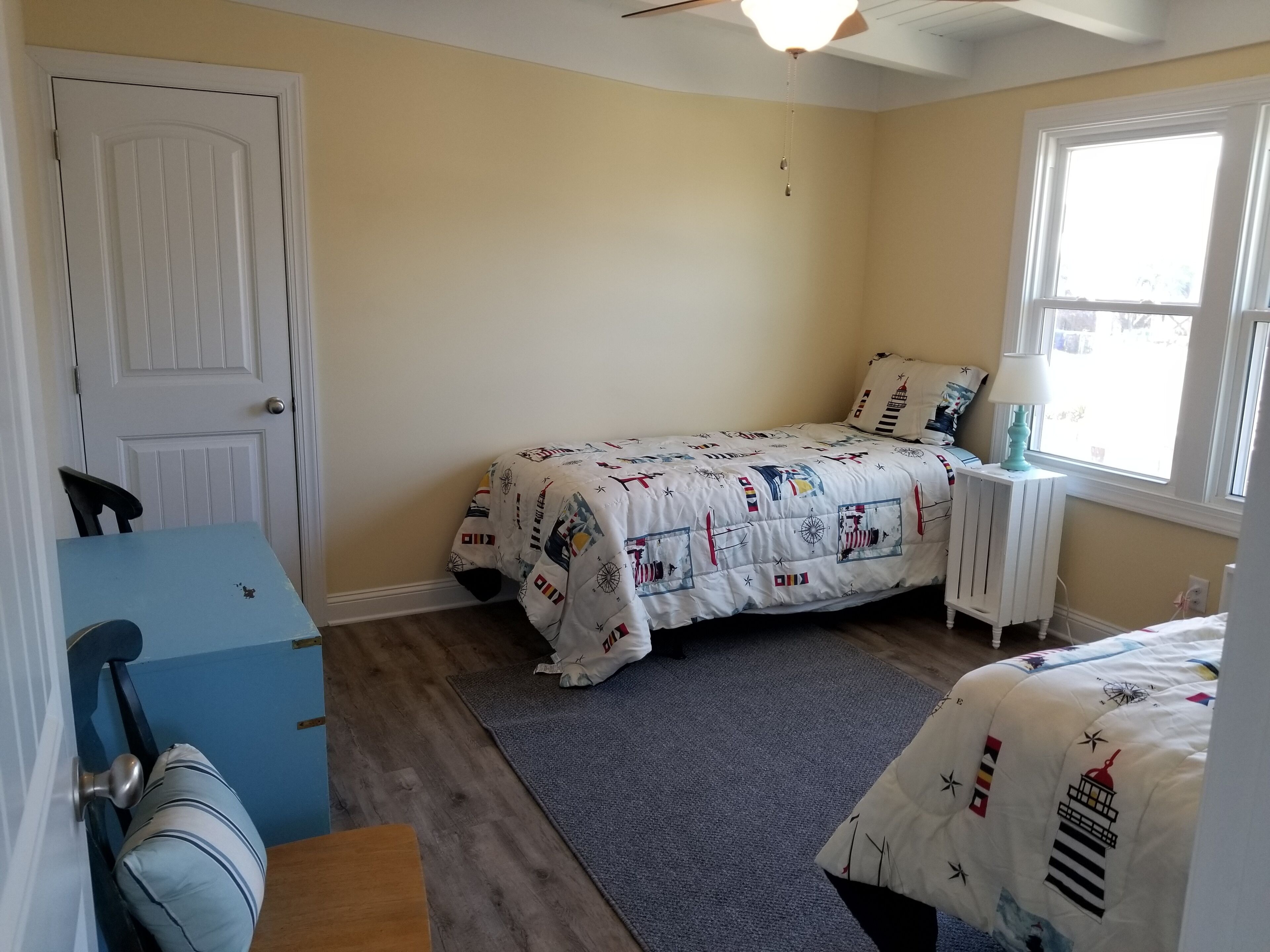 Une chambre à coucher avec un lit, un bureau, une chaise, une fenêtre et une porte.