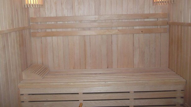 A wooden sauna with benches and two wall-mounted light fixtures. - Adddddddddddd (La Bresse)