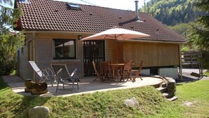 A house with a tiled roof, a covered patio with outdoor furniture, and a wooden fence. - Adddddddddddd (La Bresse)