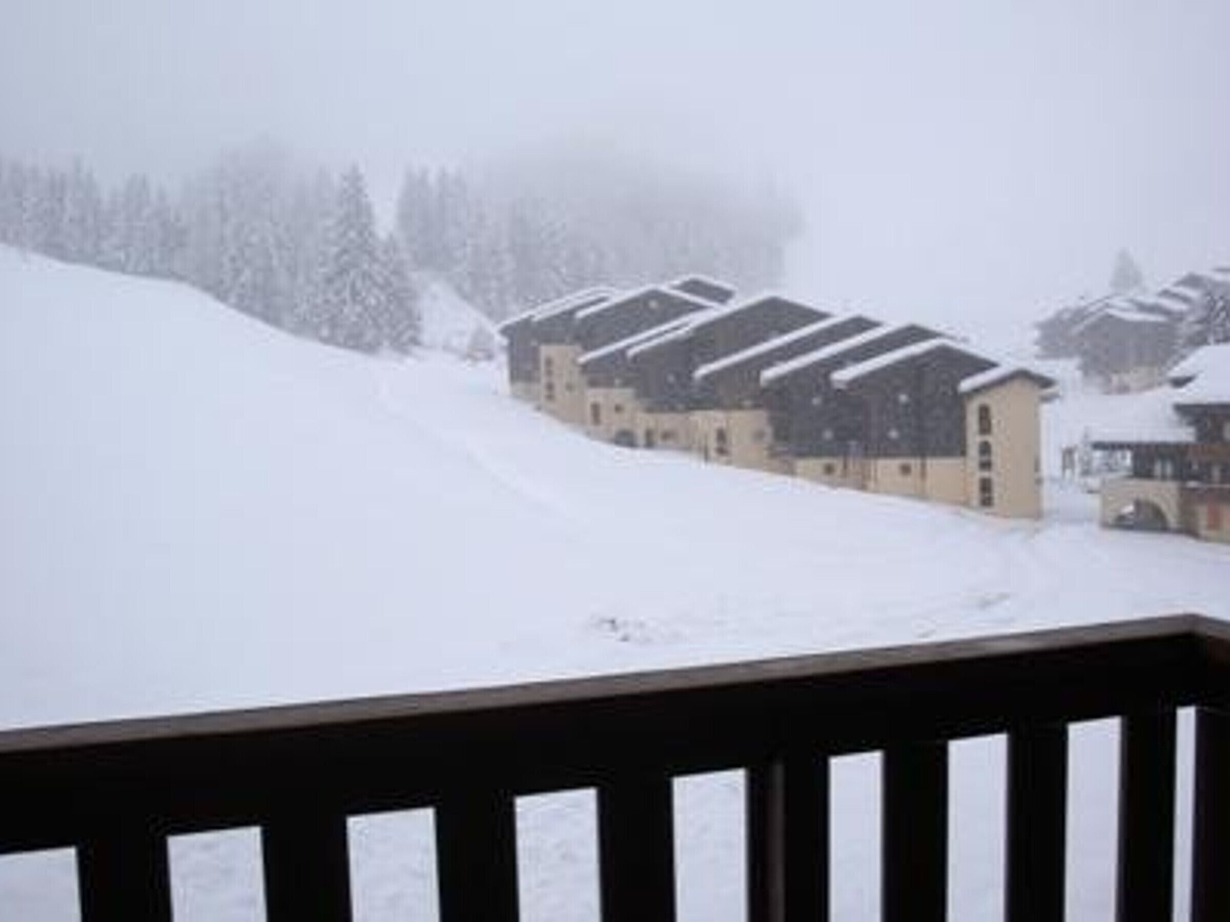 A snow-covered building with multiple balconies, likely a hotel or resort.
