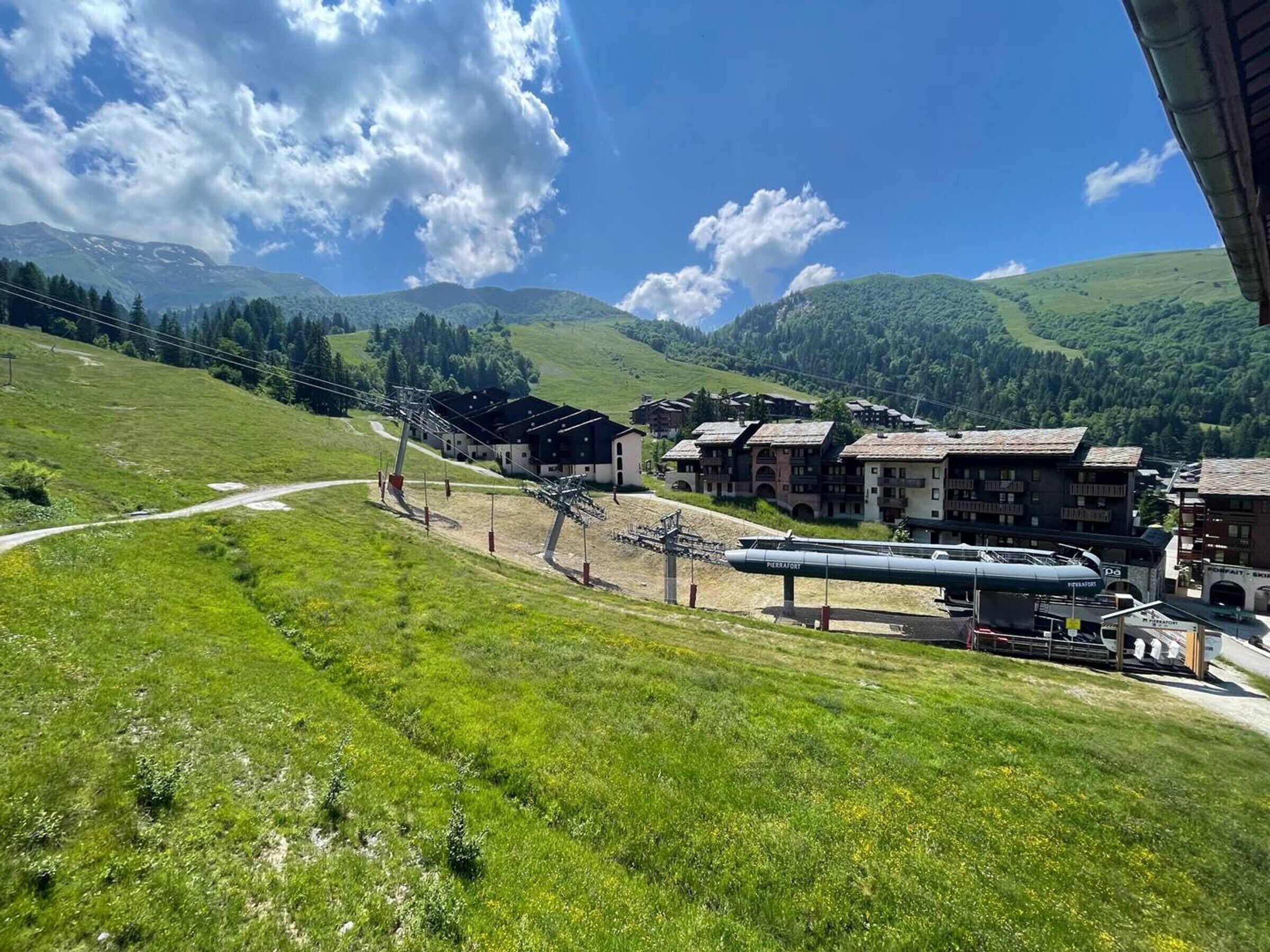 A mountainous village with traditional buildings, a ski lift, and a clear sky.