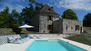 Un bâtiment en pierre doté d’une piscine, de chaises longues et d’un drapeau indiquant qu’il est interdit de se baigner.