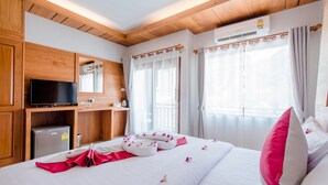 Une chambre d’hôtel avec un plafond en bois, un téléviseur à écran plat, un minibar, un lit avec une literie blanche et des oreillers roses, et une fenêtre avec des rideaux.