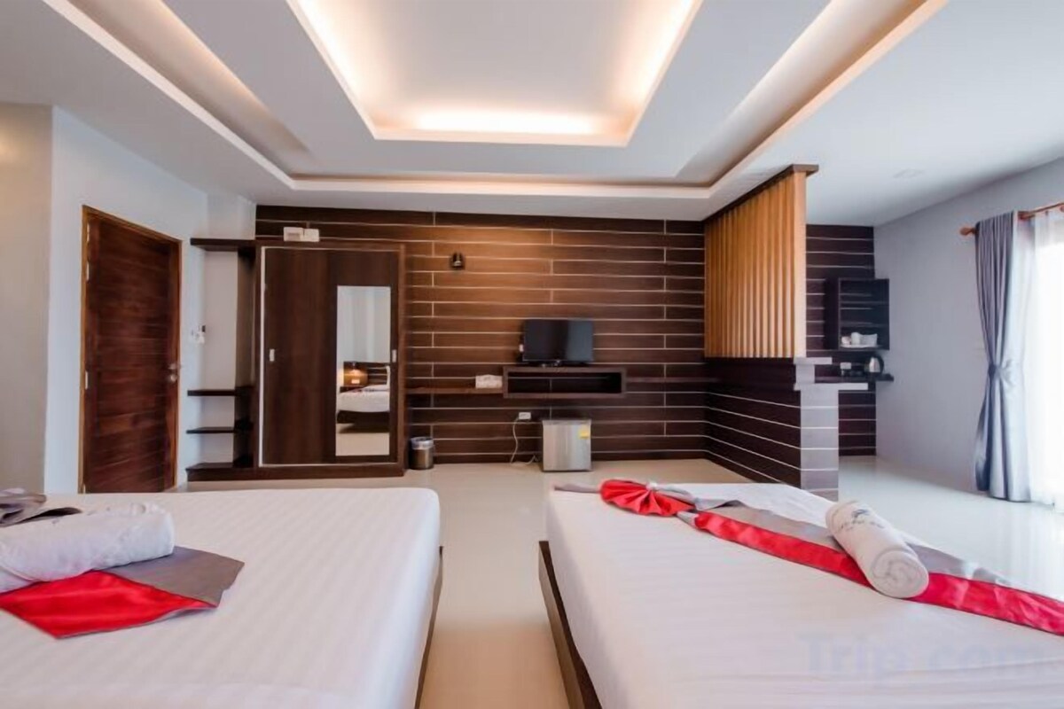 A hotel room with two beds, a TV, a wardrobe, and a mirror.