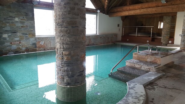 Una piscina interior con paredes de piedra y techo de madera.
