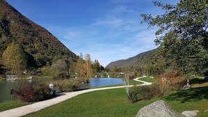 Un parque tranquilo junto al lago, con un sendero, un estanque y colinas al fondo.