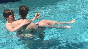 Two people in a swimming pool with clear blue water. - Modern top floor corner unit with pool view  (Scottsdale)