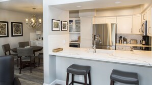 A modern kitchen with white cabinetry, stainless steel appliances, and a marble countertop. - Modern top floor corner unit with pool view  (Scottsdale)