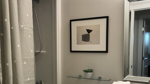 A bathroom with a shower, toilet, sink, and a framed picture on the wall.