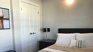 A bedroom with a bed, a nightstand, a lamp, and a door.