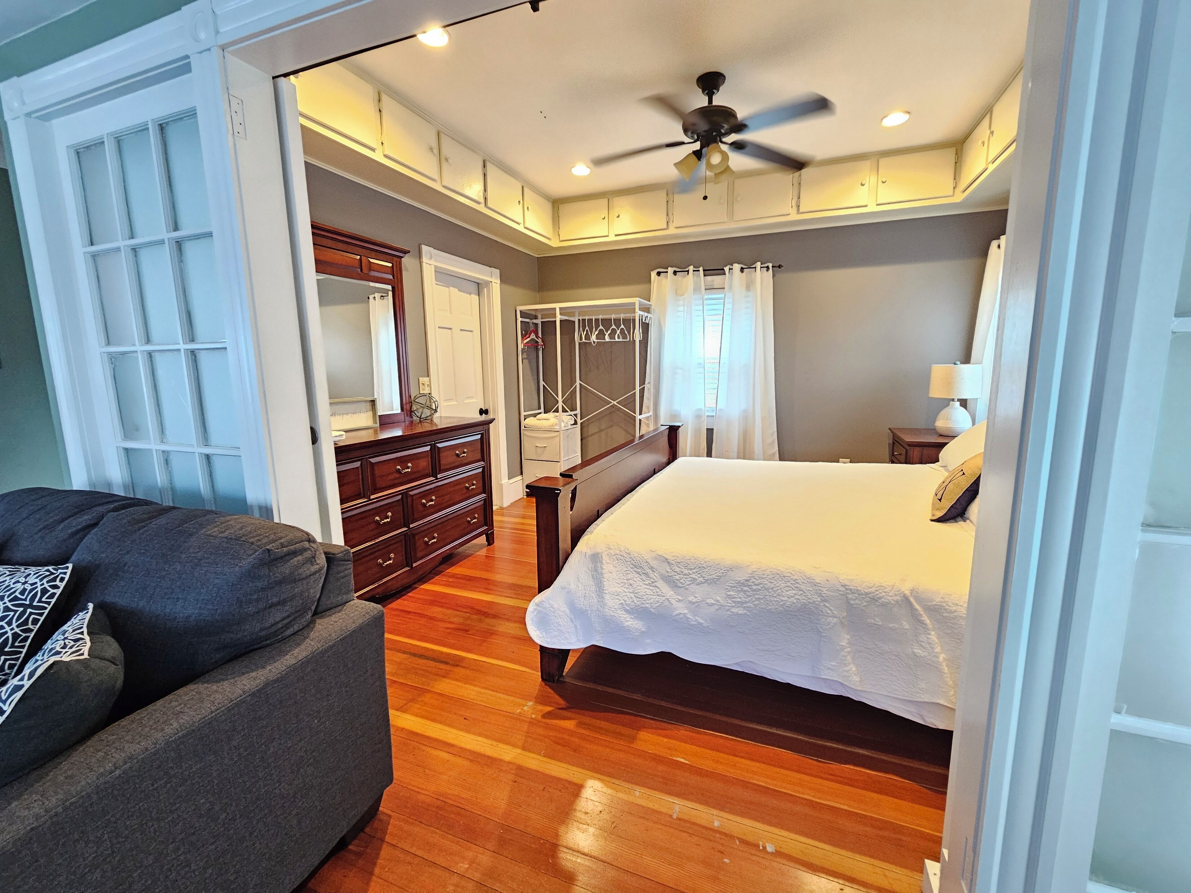 Un dormitorio con cama, cómoda, tocador y vestidor.