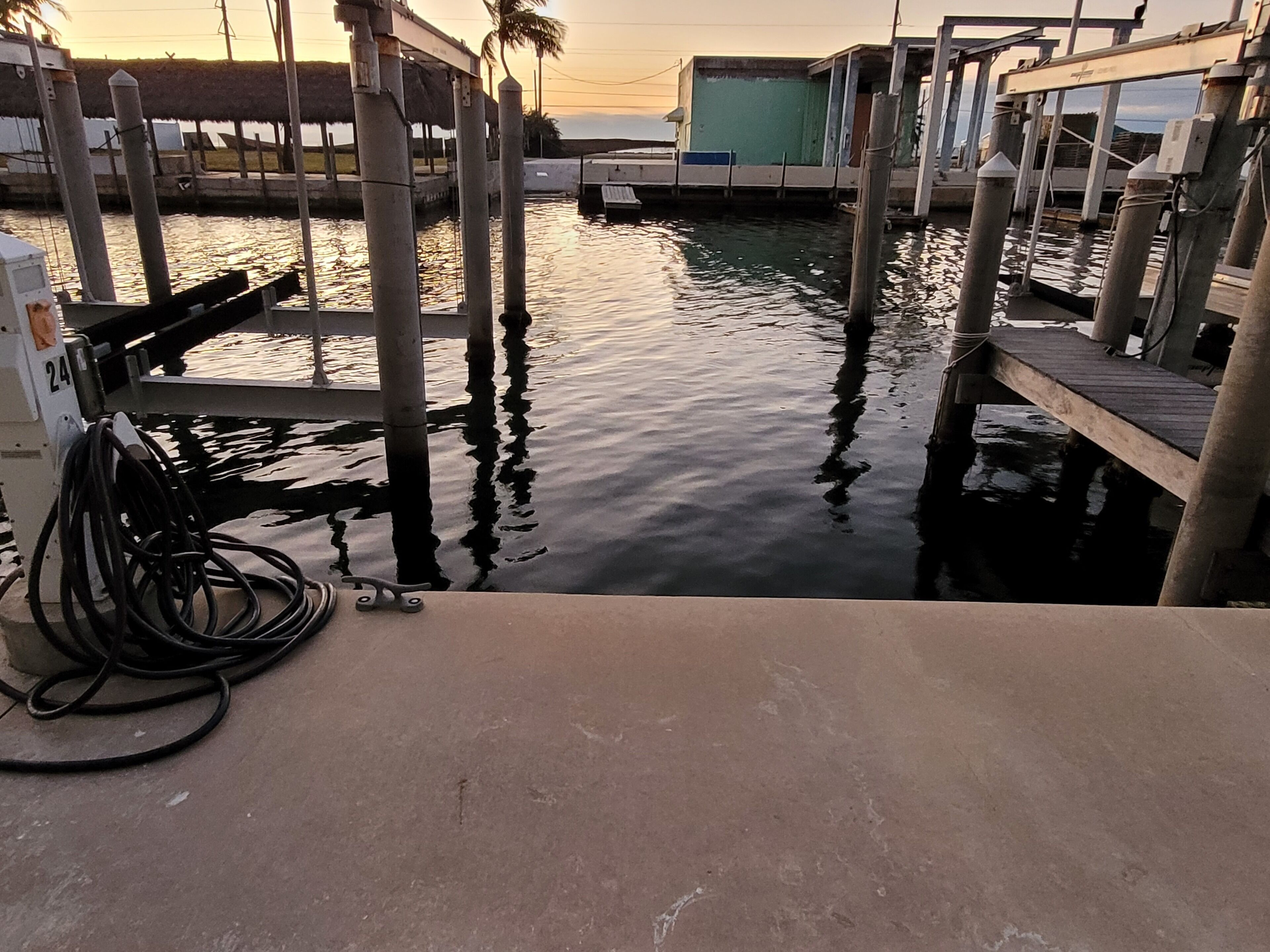 Un port de plaisance avec des bateaux amarrés, un quai en béton et une pompe à eau.