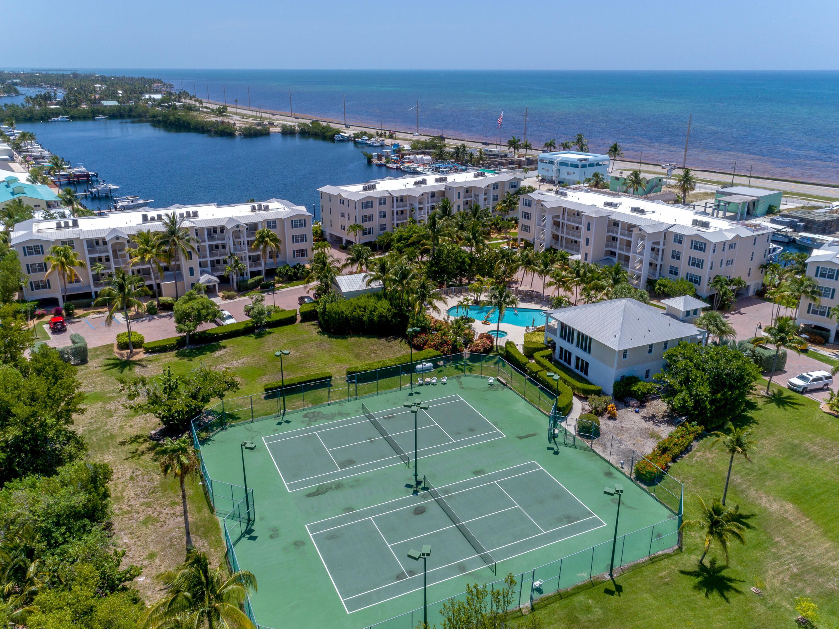 Un complexe hôtelier comprenant plusieurs bâtiments, un court de tennis et offrant une vue sur l’océan.