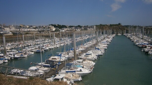 A marina with numerous boats docked along a narrow waterway, surrounded by residential buildings. - villa for 10 people (Bréhal)