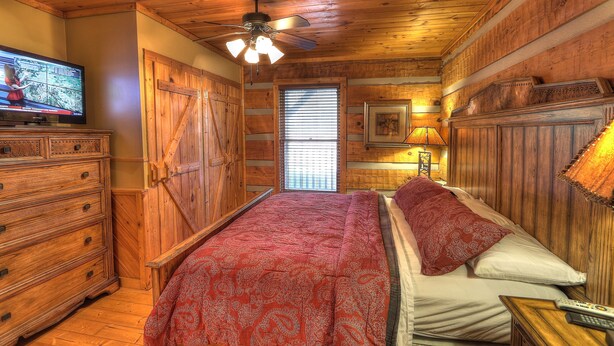 A wooden-paneled room with a bed, dresser, and a television. - Nature's Harmony #10 Cabin – Your Perfect Getaway (Sevierville)