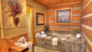 A stone bathtub with a wooden bench and towels, a wooden ceiling, and a framed picture on the wall. - Nature's Harmony #10 Cabin – Your Perfect Getaway (Sevierville)