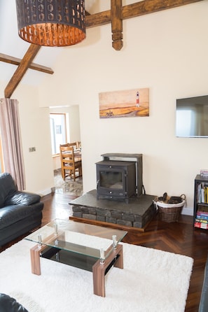 Una sala de estar acogedora con una mesa de centro de vidrio, una chimenea, un sofá de cuero y un cuadro en la pared.
