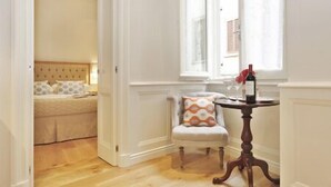 A room with a bed, a chair, and a table with a bottle. - SantaCroce Junior Luxury Suite (Firenze)