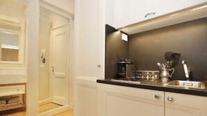 A modern kitchen with white cabinetry, a black countertop, and stainless steel appliances. - SantaCroce Junior Luxury Suite (Firenze)