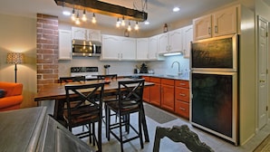 A modern kitchen with white cabinets, a black refrigerator, and a wooden dining table with chairs. - ❤️ Perfect for traveling nurses! - Wifi, AC, 4-6 minute commute to Hershey Med (Hummelstown)