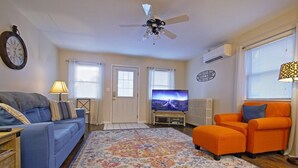 A living room with a blue sofa, an orange armchair, a television, a ceiling fan, and a decorative rug. - ❤️ Perfect for traveling nurses! - Wifi, AC, 4-6 minute commute to Hershey Med (Hummelstown)