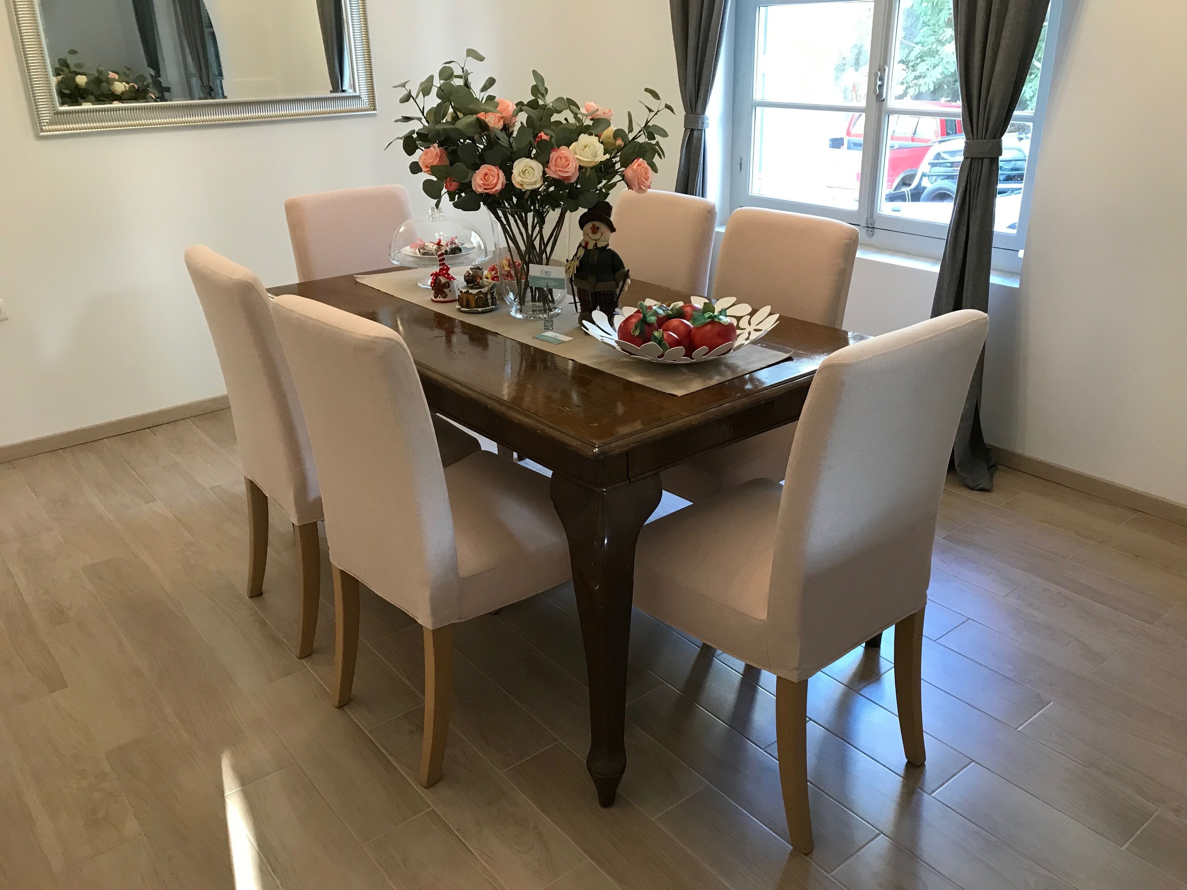 Una mesa de comedor con un centro de mesa floral, rodeada por cuatro sillas.