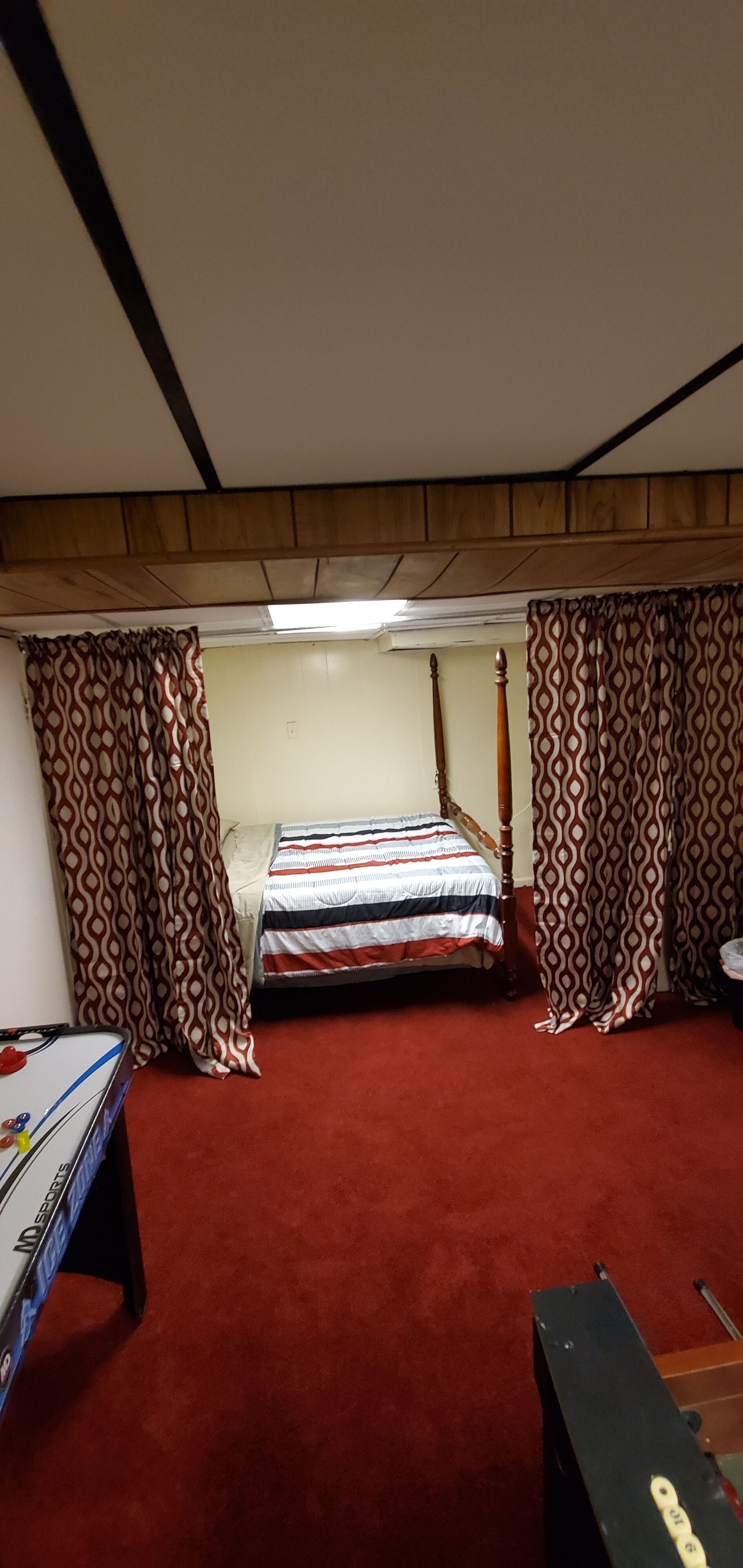 A room with a bed, a desk, and a red carpet.