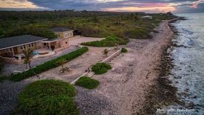Vista aérea de una propiedad costera con una casa grande, una piscina y un jardín bien cuidado.