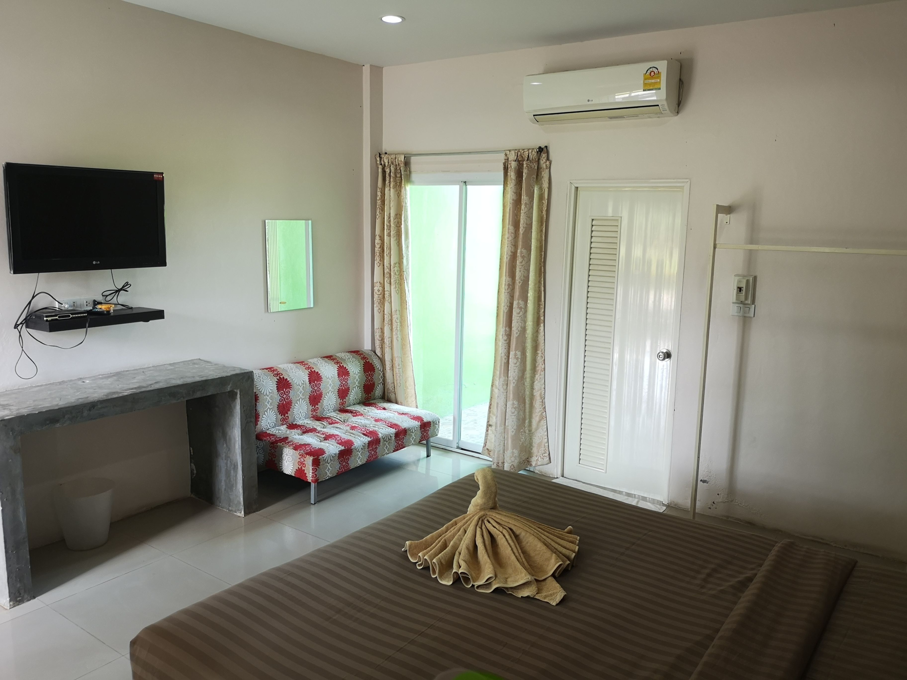 A hotel room with a bed, a desk, a television, and a window with curtains.