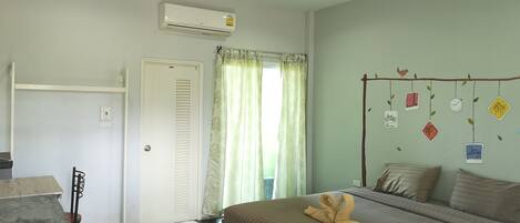 Habitación de hotel con cama, escritorio, aire acondicionado y ventana con cortinas.