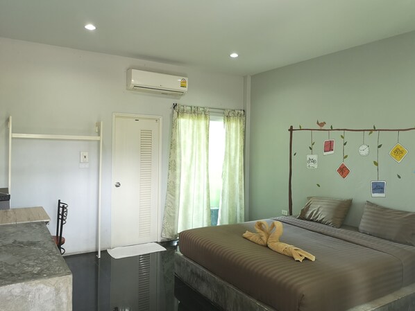Habitación de hotel con cama, escritorio, aire acondicionado y ventana con cortinas.